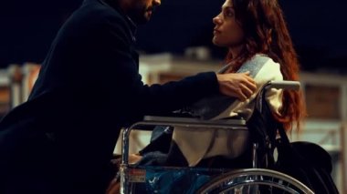 Genç bir erkekle engelli bir kadın arasında ay ışığında romantik bir öpücük.