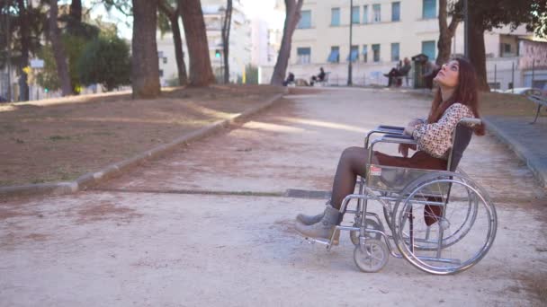 車椅子だけで公園を見ている若い女性 — ストック動画