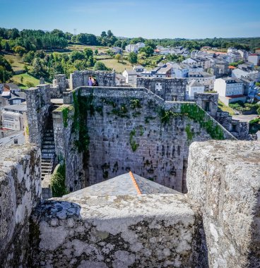 Arka planda siperleri ve köyü olan bir şatonun manzarası.