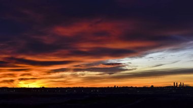Madrid şehrinin panoramik manzarası gün batımında renkli bulutlarla gökyüzü.