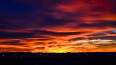 Madrid şehrinin panoramik manzarası gün batımında renkli bulutlarla gökyüzü.