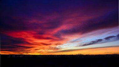Madrid şehrinin panoramik manzarası gün batımında renkli bulutlarla gökyüzü.