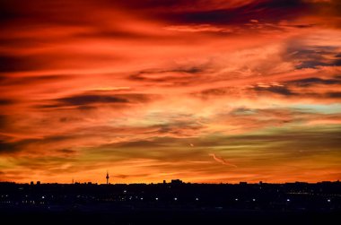 Madrid şehrinin panoramik manzarası gün batımında renkli bulutlarla gökyüzü.