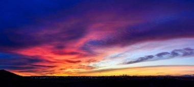 Madrid şehrinin panoramik manzarası gün batımında renkli bulutlarla gökyüzü.