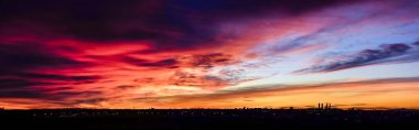 Madrid şehrinin panoramik manzarası gün batımında renkli bulutlarla gökyüzü.