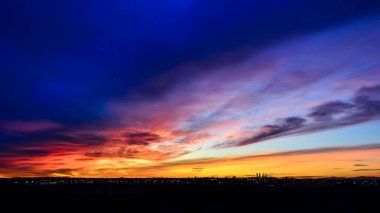 Madrid şehrinin panoramik manzarası gün batımında renkli bulutlarla gökyüzü.