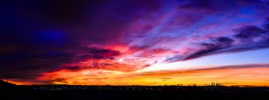 Madrid şehrinin panoramik manzarası gün batımında renkli bulutlarla gökyüzü.