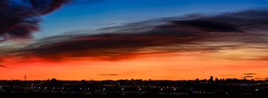 Madrid şehrinin panoramik manzarası gün batımında renkli bulutlarla gökyüzü.