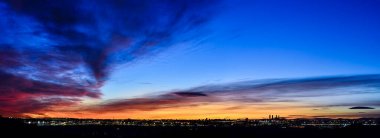 Madrid şehrinin panoramik manzarası gün batımında renkli bulutlarla gökyüzü.