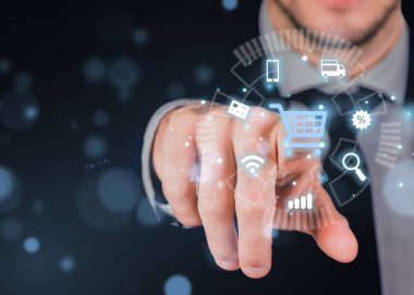 İş adamı, alışveriş arabalarının ikonlarıyla sanal arayüzde e-ticaret tuşuna basıyor, internet konseptinde online alışveriş yapıyor.