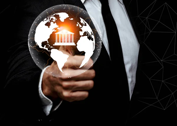 Businessman pointing transparent digital globe with bank icon, banking, finance and trading concept