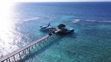 Static Drone shot of Docked Seaplane to a wooden Pier on transparent blue water, Vakkaru, Maldives. Seaplane transporting passengers to small islands from Male Airport. High quality 4k footage