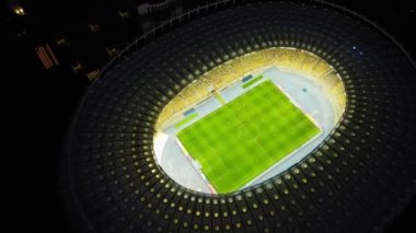 Descending Top Down view of Night Football Stadium in Kyiv, Ukraine. Drone perspective on illuminated Olympic stadium with soccer game and fans. High quality 4k footage