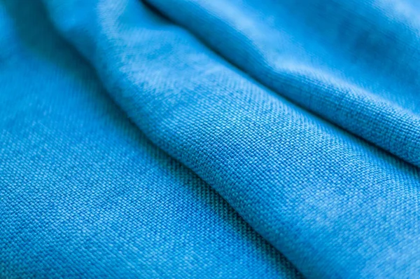 Natural blue cotton fabric stacked in layers. Wrinkled fabric background. Closeup