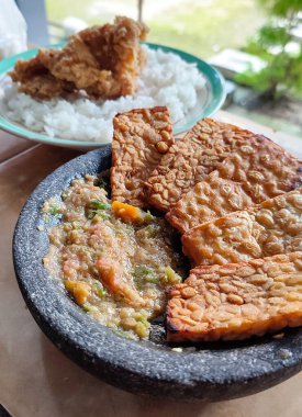 Lezzetli ev yapımı Tempe Penyet, geleneksel Endonezya yemekleri. Kızarmış Tempeh Sambal ile bir havan topu ezdi (Ground Red Chilies, Shallots, soğan ve karides ezmesi))