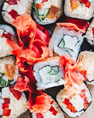 Suşi, salatalık, somon, yılan balığı, ton balığı ve zencefilli makarna. Siyah arka planda suşi rulosu.