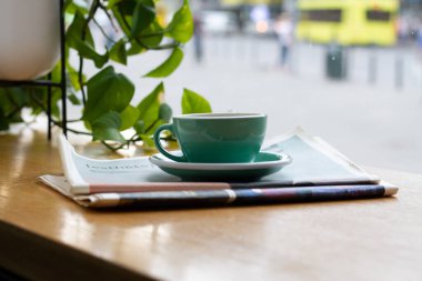 A cup of coffee or tea in cafe around the flowerpot and window. Work break with good view.