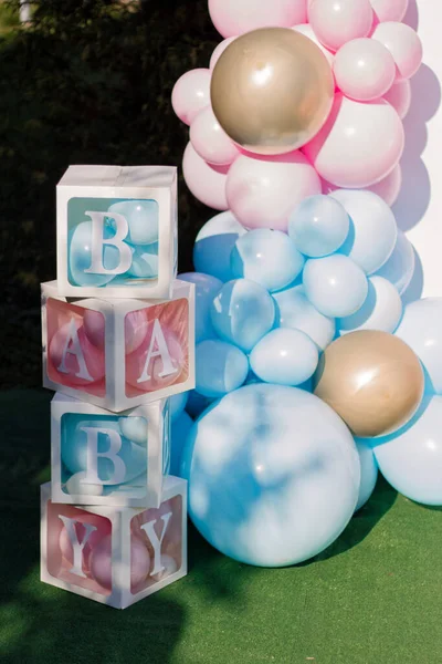 Photo zone for a gender party. A stand for a baby shower. Pink and blue balloons for children. Ideas for organizing a gender reveal. Details of decoration.