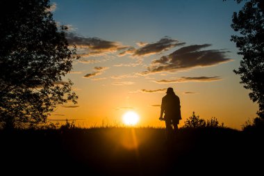 Bir bisikletçi, gün batımının güzel bir konturunun arka planına karşı bir tarlada yol alır. Güzel gün batımı. Doğanın fotoğrafı. Hız teması.
