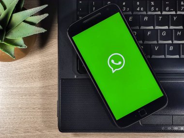 Whatsapp, ahşap arka planda Not Defteri olan akıllı telefon ekranını çalıştır. WhatsApp akıllı telefonlar için çok platformlu anlık mesajlaşma ve sesli arama uygulaması.