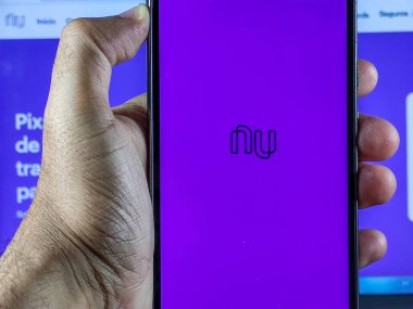 Nubank uygulamalı akıllı telefonu olan adam akıllı telefon ekranında ev ekranını açık tutuyor.