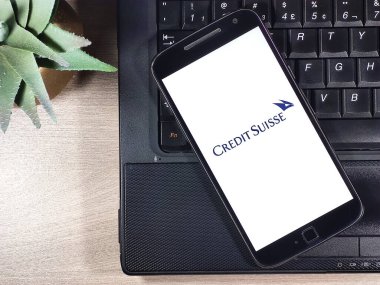 Credit Suisse, ahşap masadaki defterin üstündeki akıllı telefon ekranında. Credit Suisse Group bir İsviçre yatırım ve finans hizmetleri bankasıdır..
