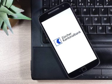 Zrcher Kantonalbank ahşap masadaki defterin üstündeki akıllı telefon ekranında. Zürih Kanton Bankası en büyük kanton bankasıdır..