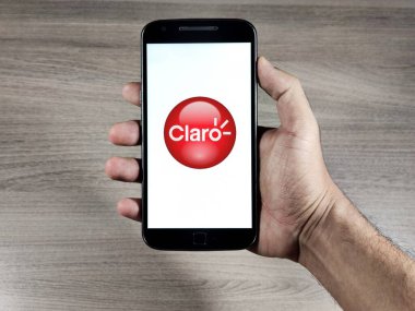 Akıllı telefon ekranında operatör Claro logosu var. Claro cep telefonu, sabit telefon, geniş bant ve ödemeli televizyon uzmanıdır..