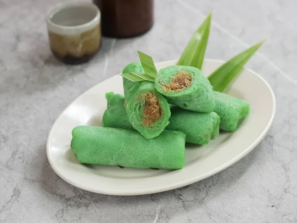 kue dadar gulung, glutinous rice, hindistan cevizi ve palmiye şekerinden yapılmış bir tatlı. Malezya, Endonezya ve Singapur 'da popülerdir. mermer arka planda servis edilir