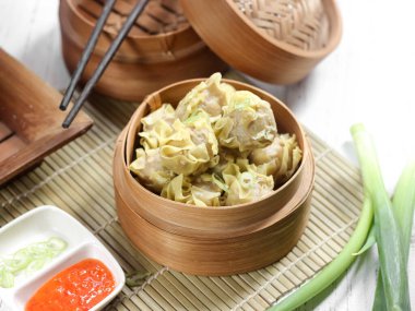 Siomay ayam, tavuk ve karidesin ana bileşenleriyle buğulanmış hamur köftesi. Ahşap arka planda geleneksel bambu buharlı vapurda servis ediliyor. Seçici odak