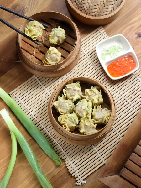 Siomay ayam, tavuk ve karidesin ana bileşenleriyle buğulanmış hamur köftesi. Ahşap arka planda geleneksel bambu buharlı vapurda servis ediliyor. Seçici odak