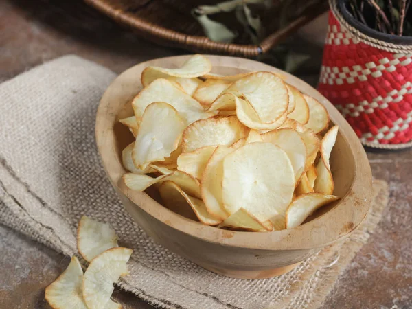 Keripik singkong. Cassava cipsi ya da tapyoka cipsi, ince dilimlenmiş ve kızarmış Cassava 'dan yapılan geleneksel bir aperatiftir. Tahta kasede servis edilmiş. Seçici odak