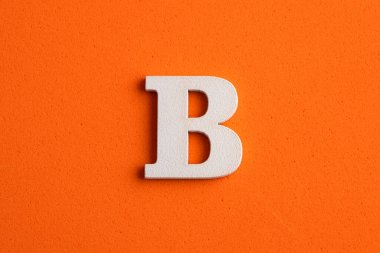 Alfabe harfi B - Turuncu köpüklü arka planda beyaz ahşap parça