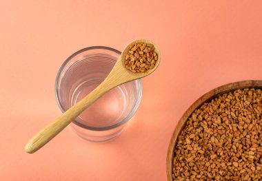 Çemen otu tohumlu kaşık ve bir bardak filtreli su.