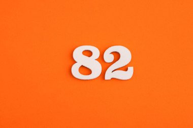 White wooden number 82 on eva rubber orange background
