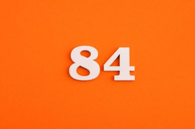 White wooden number 84 on eva rubber orange background
