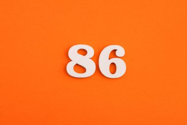White wooden number 86 on eva rubber orange background