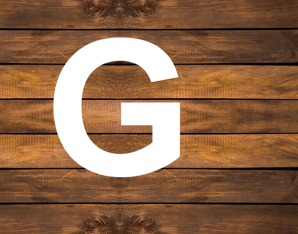 Tahta zemin üzerinde beyaz delikte alfabenin G büyük harfi