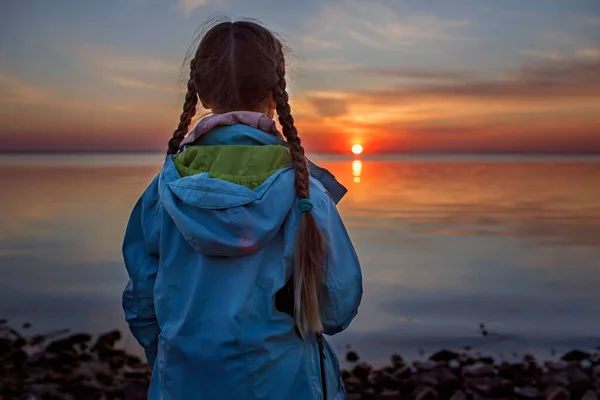 Girl stands on seashore and enjoys the sunset, escape to nature, deep in thoughts, time to be alone — Stock Photo, Image