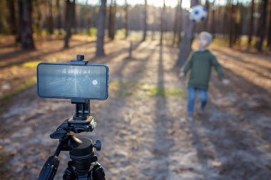 Çocuk sosyal medya ve spor blogcusu paylaşmak için akıllı telefonlu viral video filmini topa vurup kaydediyor.
