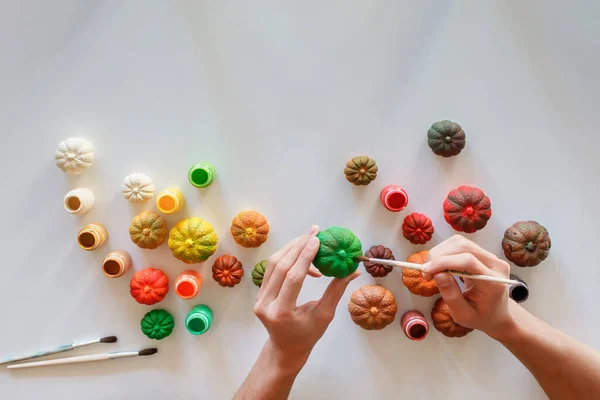Joven artista pinta calabazas de yeso DIY en los colores de la paleta de otoño, ornamento Día de Acción de Gracias —  Fotos de Stock