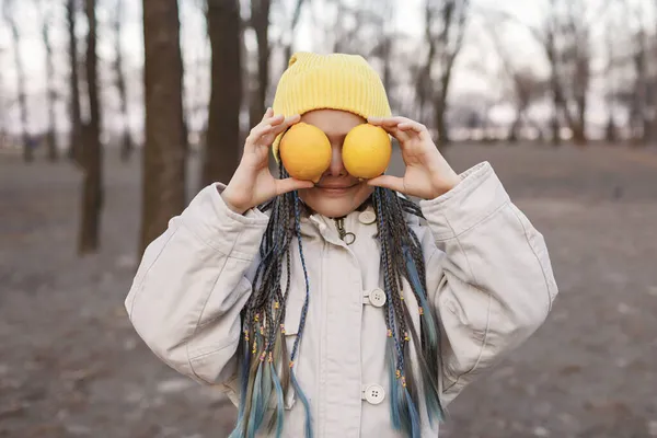 Portret emocjonalny dziewczynki z żółtymi owocami w parku, jesienny niedobór witamin u dzieci, dieta kolorystyczna — Zdjęcie stockowe