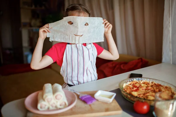 Девушка готовит колбасу в тесте из филло на завтрак, маленький шеф-повар наслаждается вкусной закуской — стоковое фото