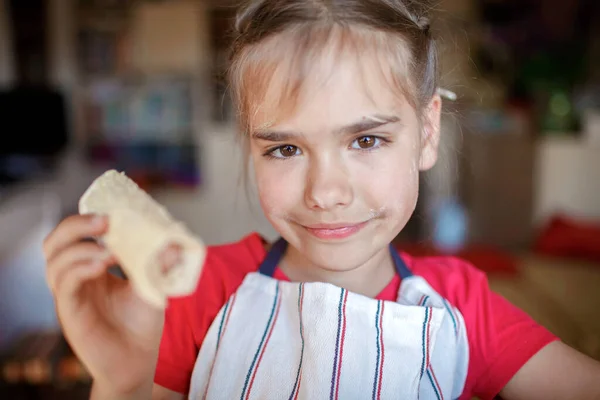 Chica cocinando salchicha enrollada en phyllo pastelería para el desayuno, poco chef disfruta de sabrosa merienda — Foto de Stock