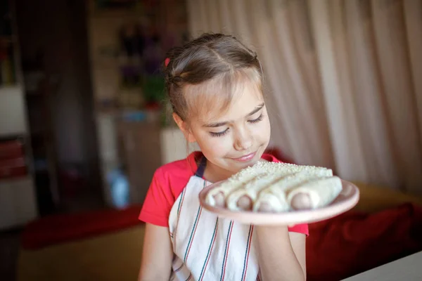 Girl cooking sausage rolled in phyllo pastry for breakfast, little chef enjoys tasty snack — Stock Photo, Image