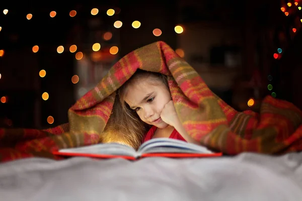 Ребенок читает книгу на кровати — стоковое фото
