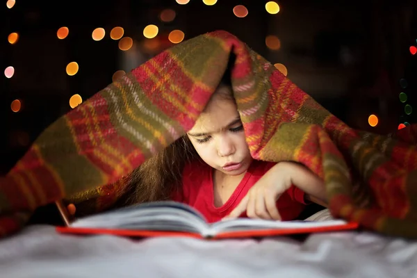 Ребенок читает книгу на кровати — стоковое фото