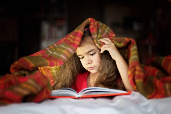 Criança lendo um livro na cama — Fotografia de Stock