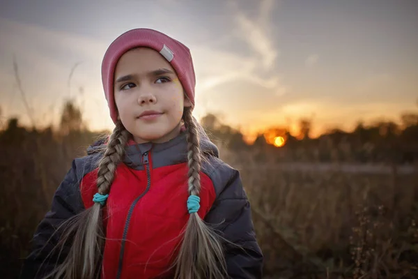 Retrato de niña preadolescente pensativa de pie entre un prado seco sobre el hermoso atardecer de otoño — Foto de Stock