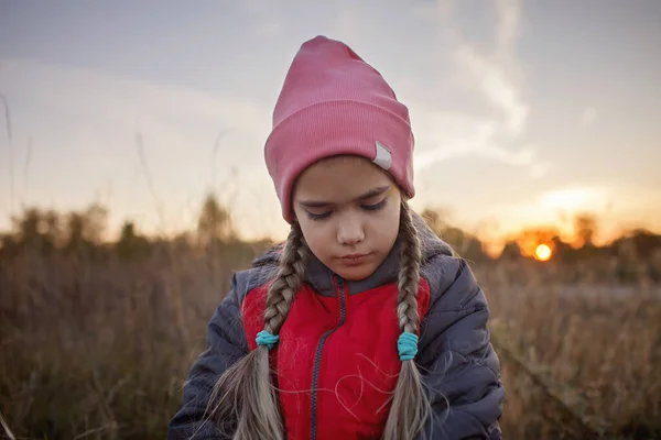 Retrato de niña preadolescente pensativa de pie entre un prado seco sobre el hermoso atardecer de otoño — Foto de Stock